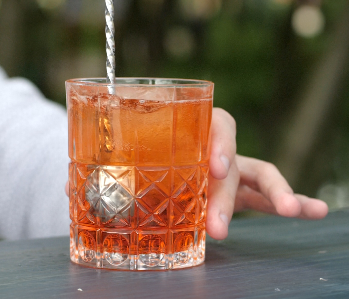 person stirring beverage in glass